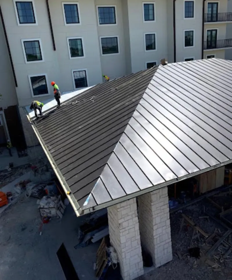 Crew installing standing seam metal roof panels on a commercial project in Lombard